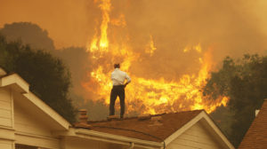 Standing on a rooftop, a man looks at the Springs fire's approaching flames in California Friday. The wildfire, reportedly, 20 percent contained, might be weakened by high humidity and cooler temperatures Saturday.